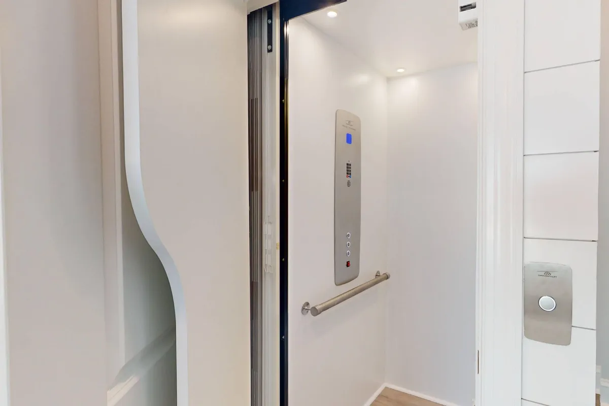 An interior view of the home's elevator, focusing on the control panel and handrail. The clean, functional design signals accessibility and convenience for all guests.