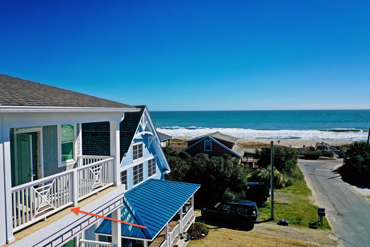 A serene balcony view with an ocean backdrop, a sturdy railing, and a blue roof visible below. The scene captures the tranquility of enjoying morning coffee or evening breezes while gazing at the Atlantic.