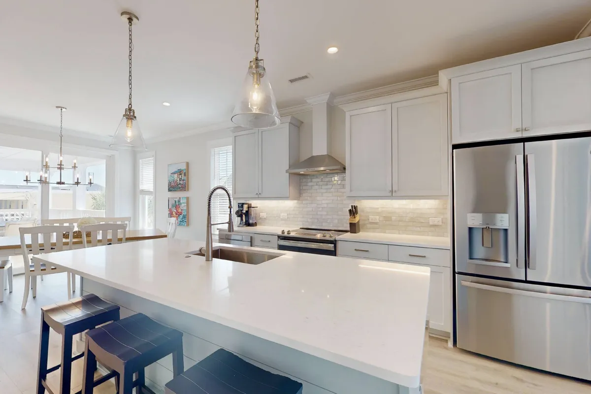 A welcoming kitchen scene focused on a large island countertop, modern stainless steel appliances, pendant lighting, and stylish cabinetry. The setting feels functional and homey, ideal for both meal prep and family interactions.