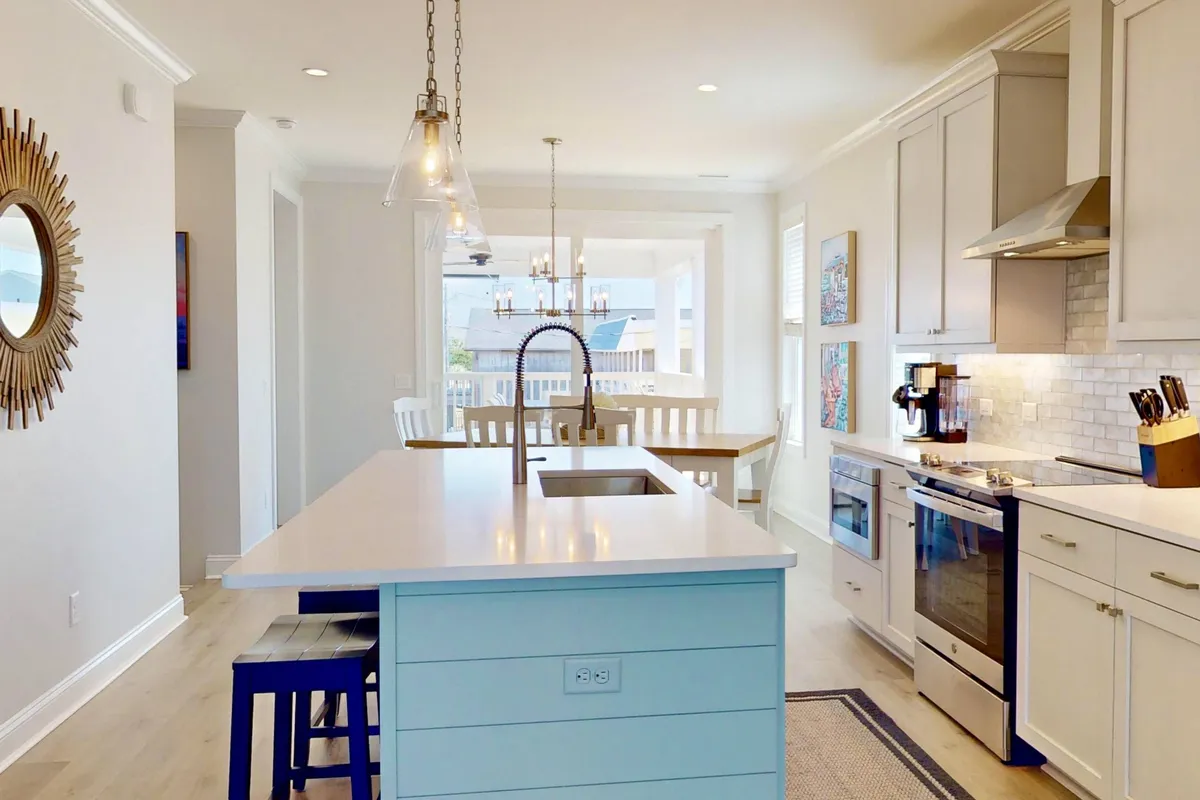 A beautifully designed kitchen and dining area that blends a contemporary island, sleek stainless steel appliances, a chandelier, and decorative artwork. The space invites family gatherings and socializing, underlining the home's flexibility for entertaining.