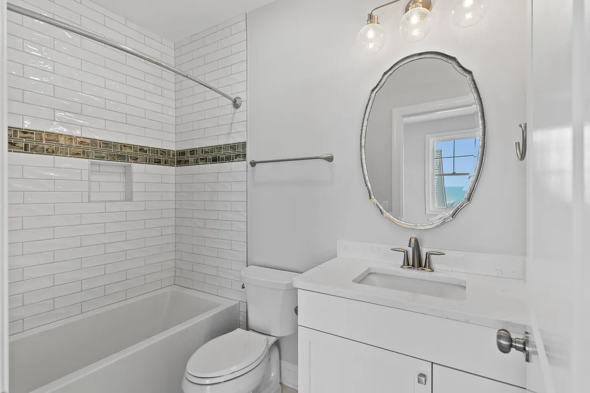 A clean and modern bathroom with a bathtub, mirror, sink, and tasteful lighting. The space is designed for relaxation and personal care, with a layout that promises comfort and privacy.